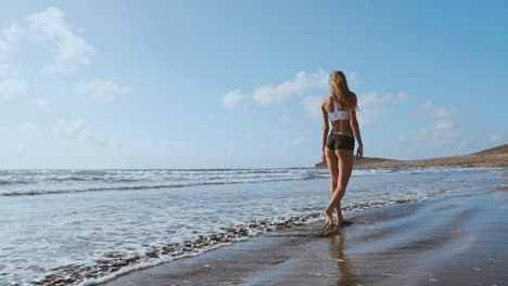 Woman-bare-foot-walking-on-the-summer-beach.-close-up-leg-of-young-woman-walking-along-wave-of-sea-water-and-sand-on-the-beach.-Travel-Concept.